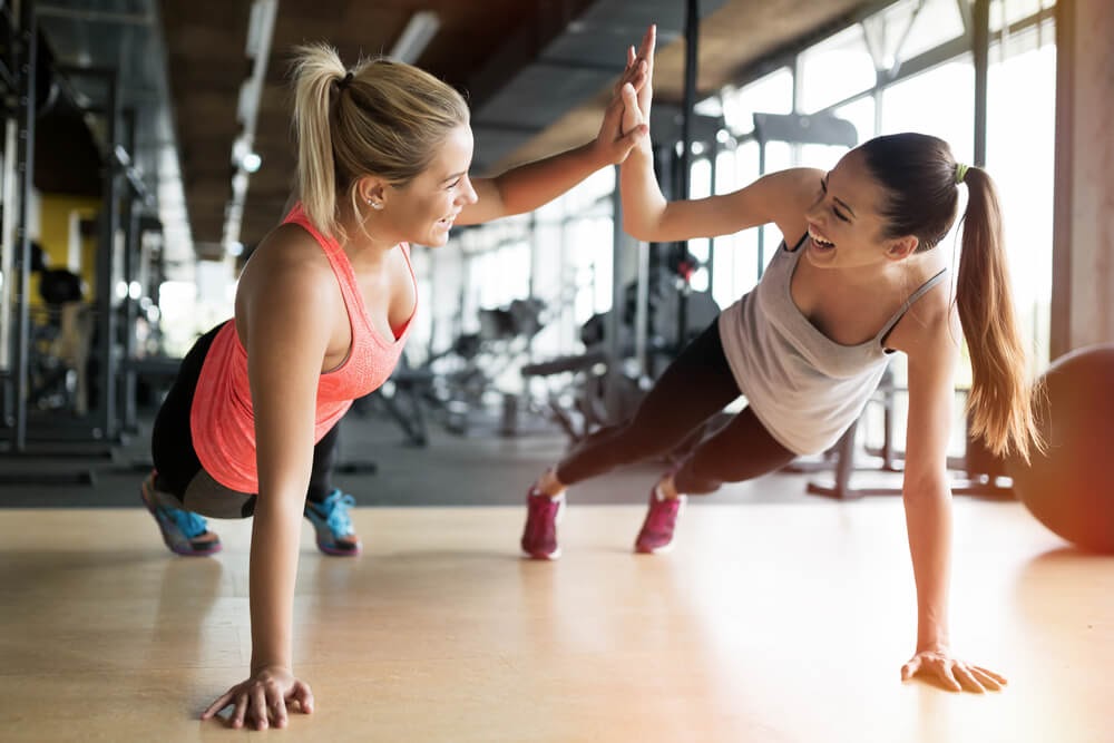 2 woman high fiving with planking