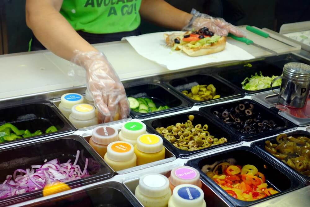 Worker at Subway making a sandwich