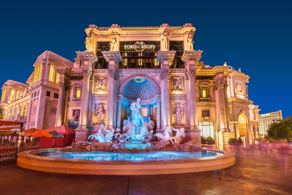 Large marble building with statues and glowing pond in front