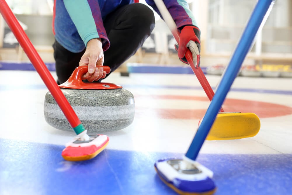 Blue and red curling stone and brooms