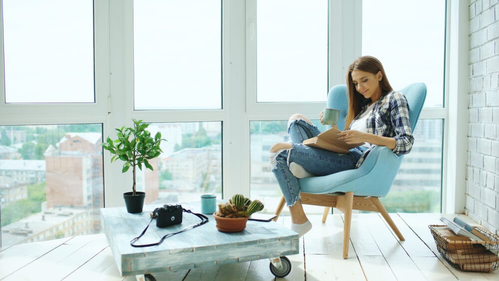 Young woman sitting in blue chair reading