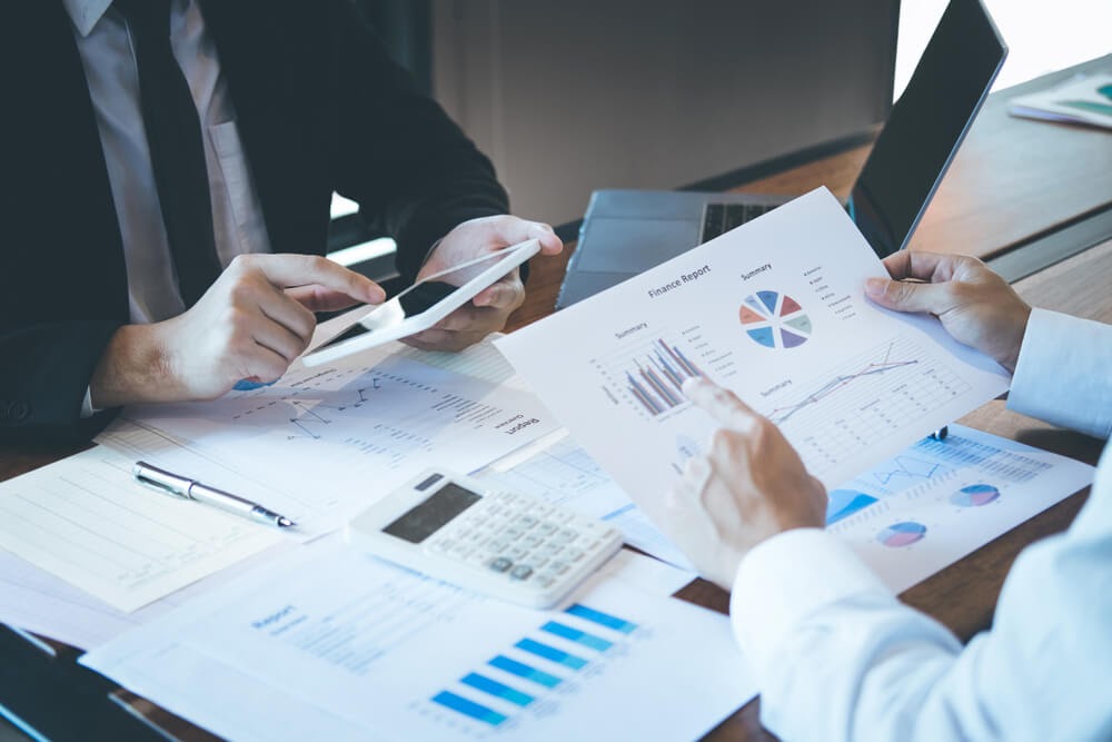 Professionally dressed people look over paperwork at desk