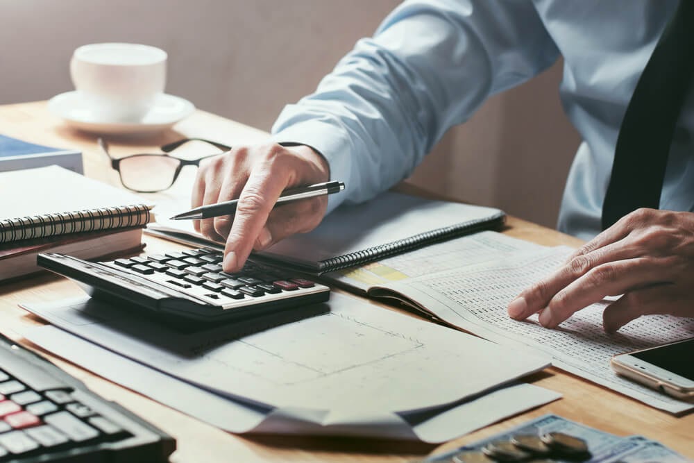 Desktop with paperwork and person using calculator