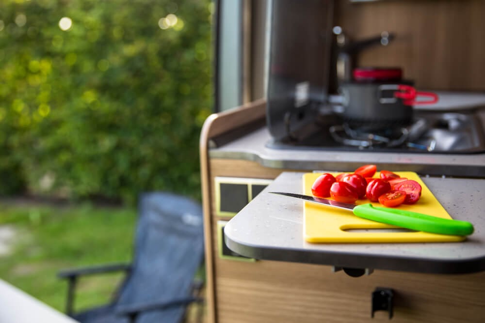 Photo of small cutting board, in tiny kitchen, with red cherry tomatoes.