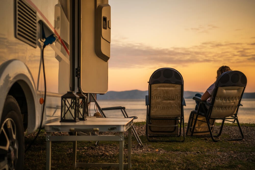 RV at sunset, two camp chairs looking over the water.