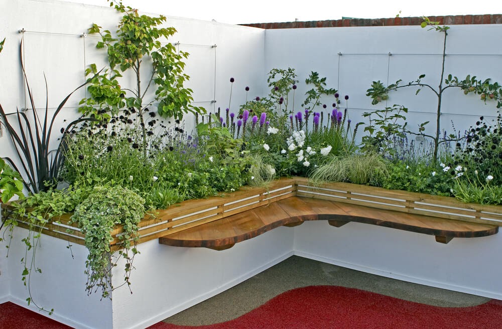 Raised corner bed with flowers in purple tones.