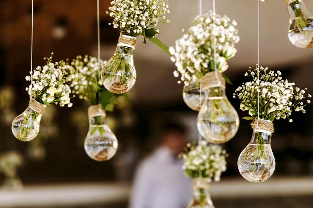 Baby's breath in lightbulbs hanging on strings.