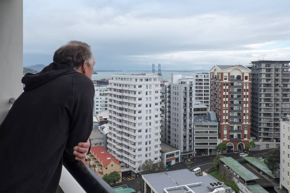Man looks over city from balcony.
