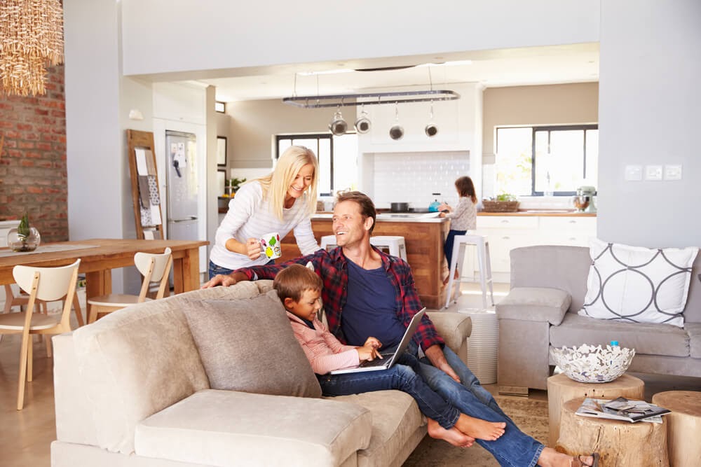 Family sit smiling together in a living room
