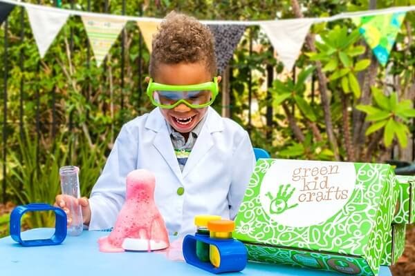 Green Kids Craft box with kid doing a volcano experiment.
