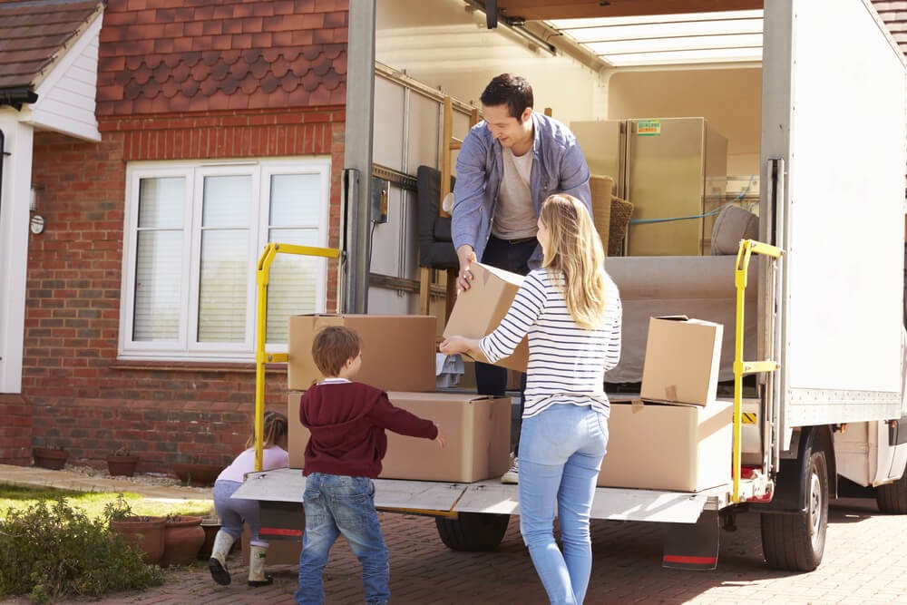 Family unloading moving boxes from a moving truck.