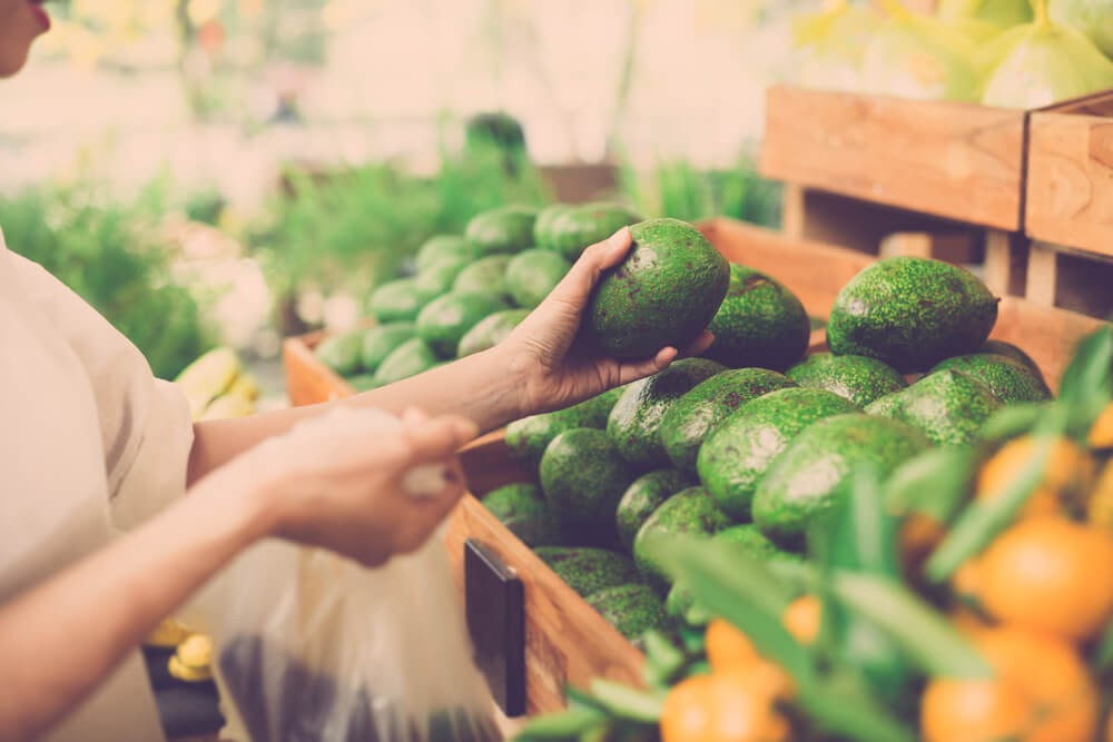 Person shopping for avocados.