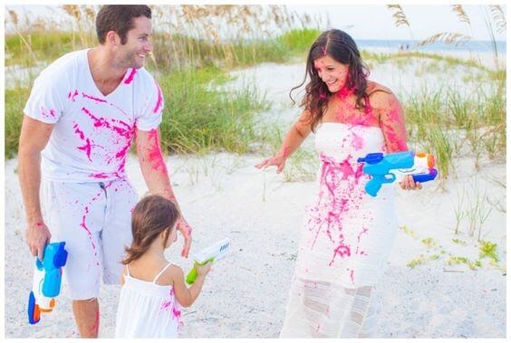 Family squirting pink paint through squirt guns on each other.