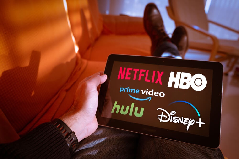 Man holding tablet showing different streaming services