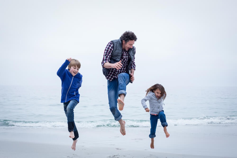 Dad and children frolicking on beach