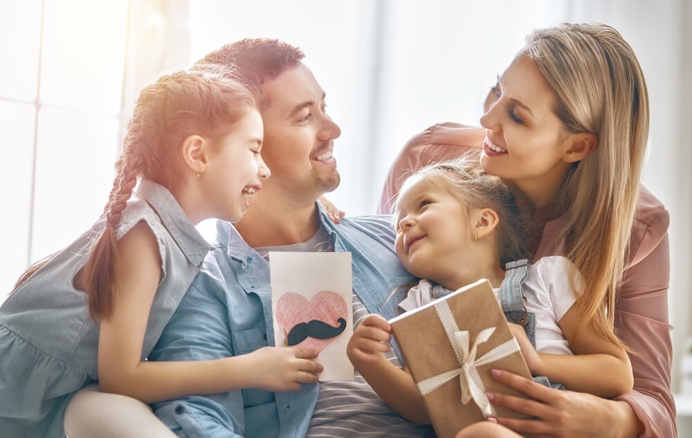 Family on couch giving dad cards