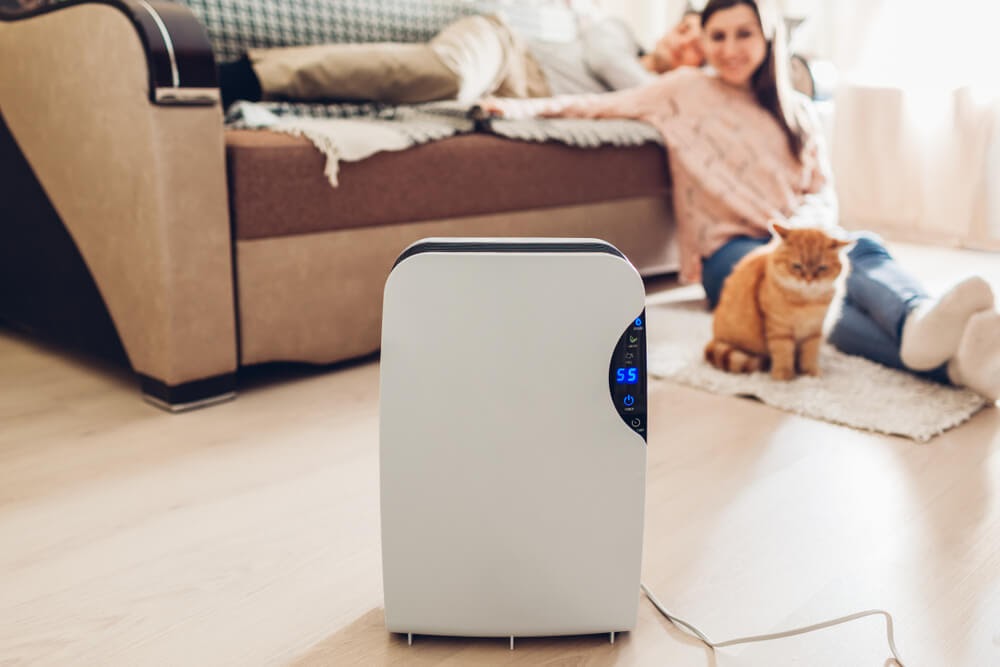 Woman and cat looking happily at their air purifier