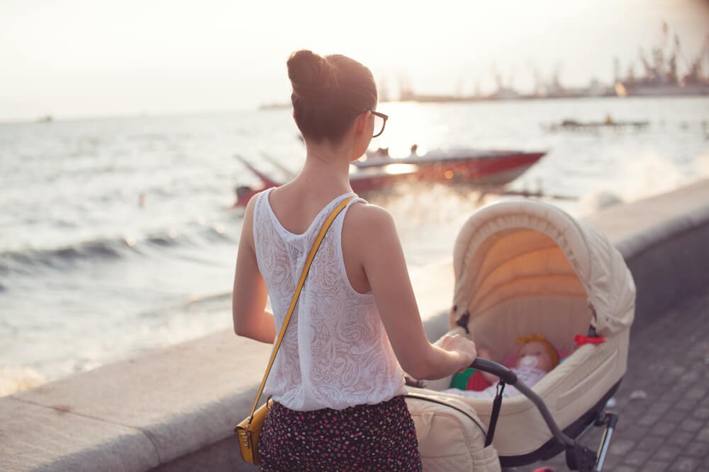 Woman pushing stroller next to lake