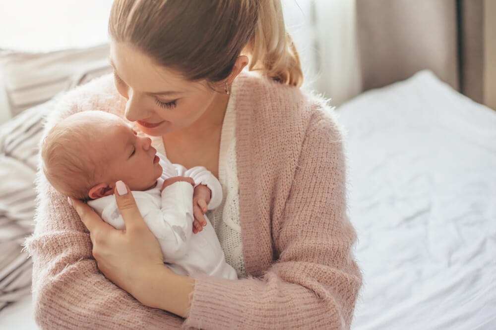 Woman snuggling her baby in bed
