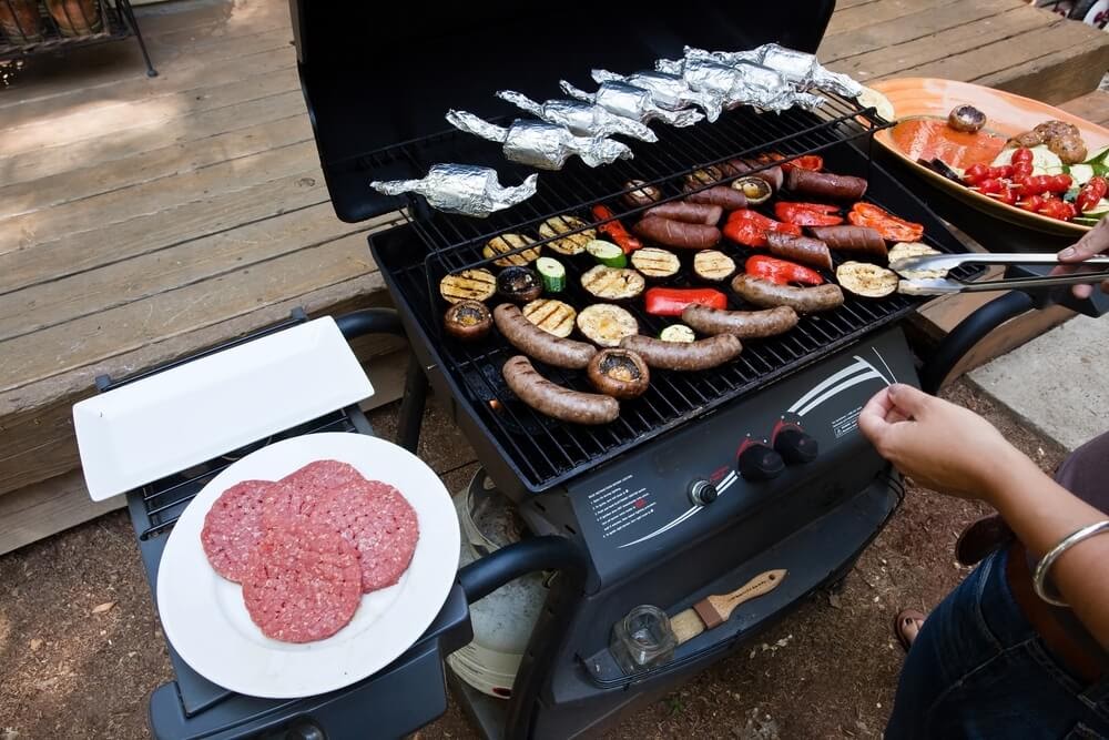 Fully stocked gas grill with meat and veggies