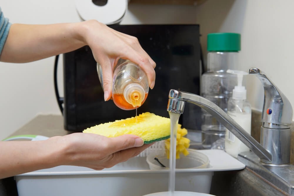 Woman squeezing dish soap onto sponge