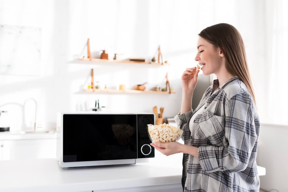 Woman enjoying popcorn from her freshly cleaned microwave