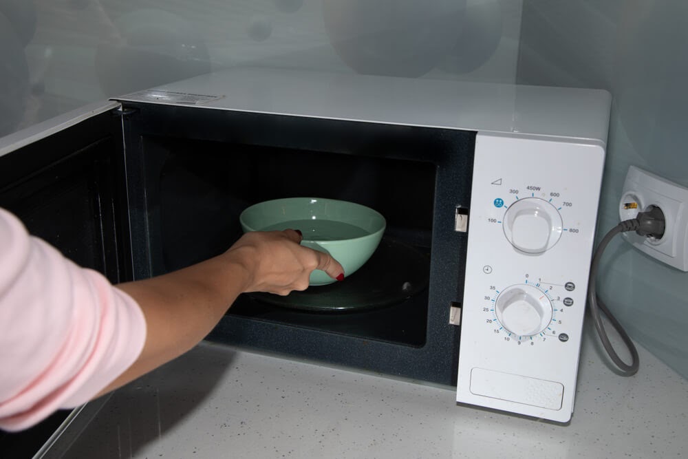 Someone putting a bowl in their microwave