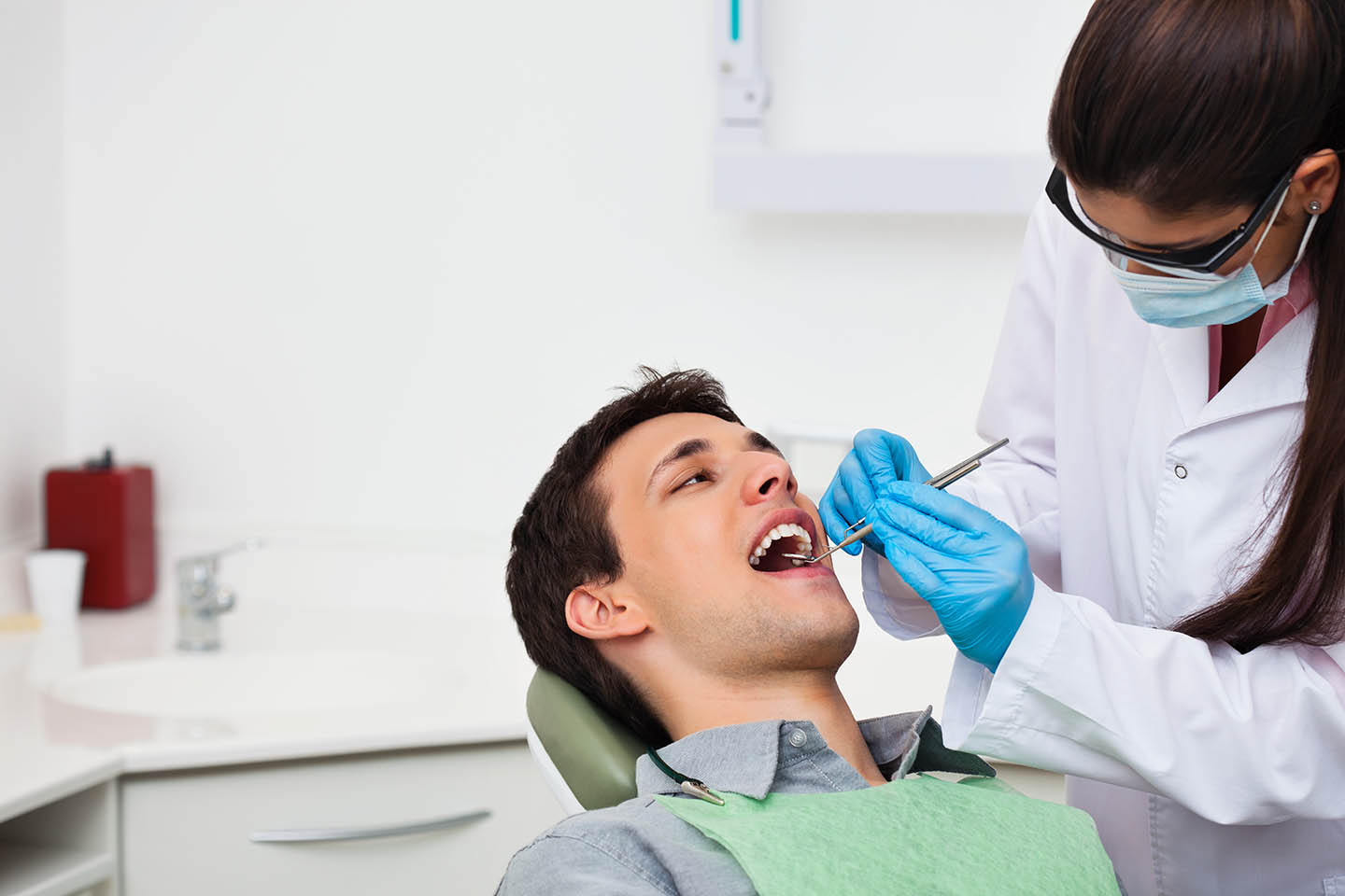 dental hygienist checking out a male patient's teeth