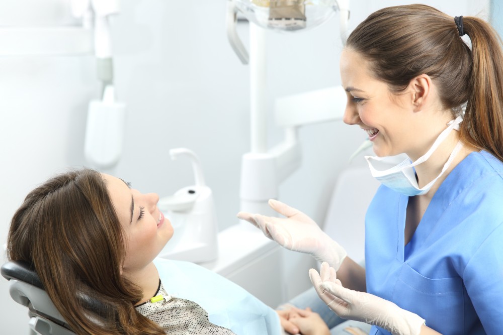 a woman patient in dental chair talking to woman hygienist