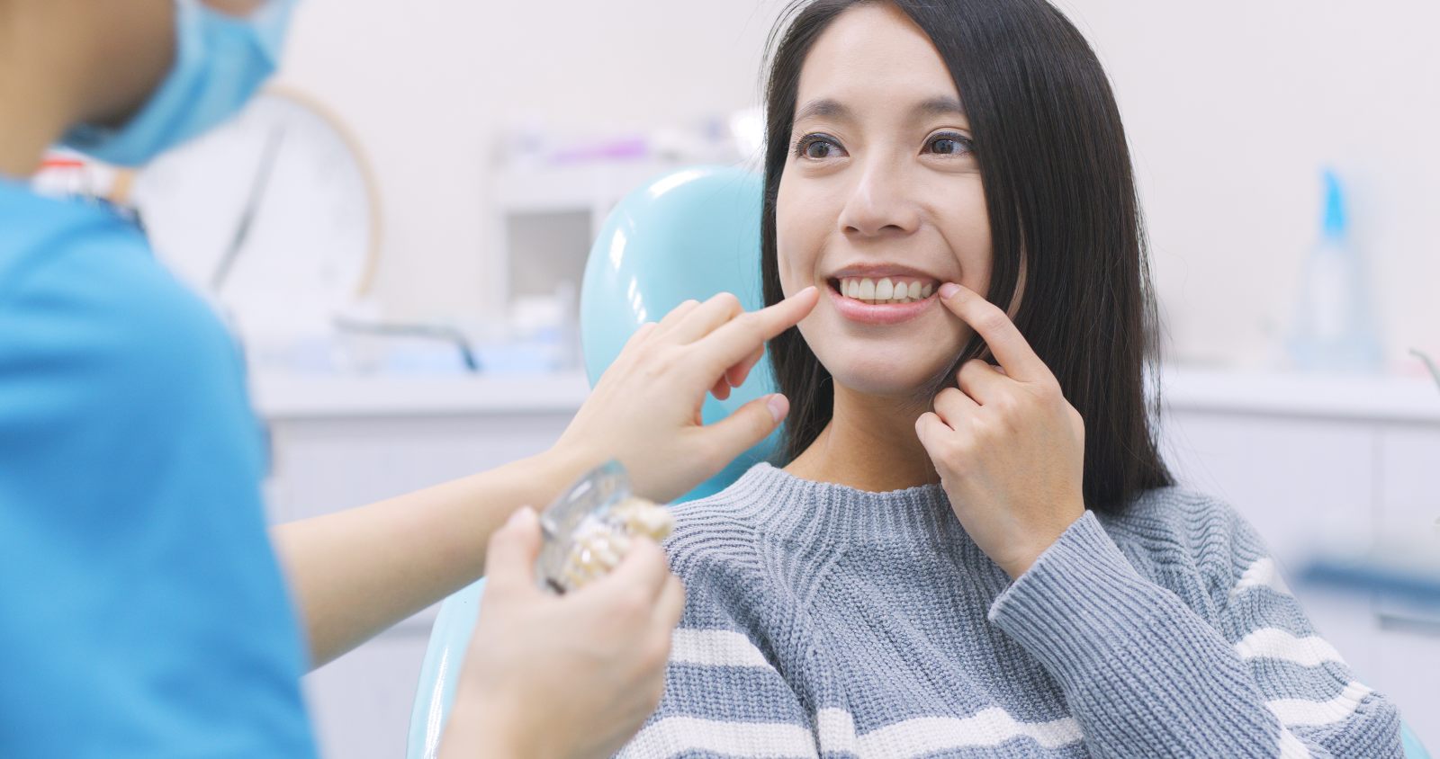 a woman patient pointing at her teeth talking to a dentist