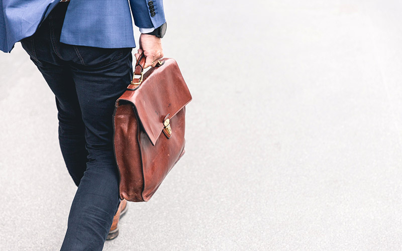 Man walking with brown business bag - Photo by Marten Bjork on Unsplash