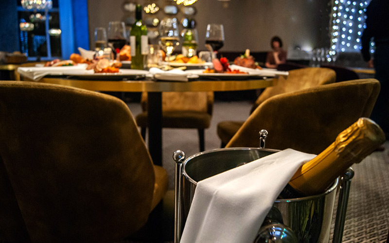 A table dressed for a party completed with a bottle of bubbles.