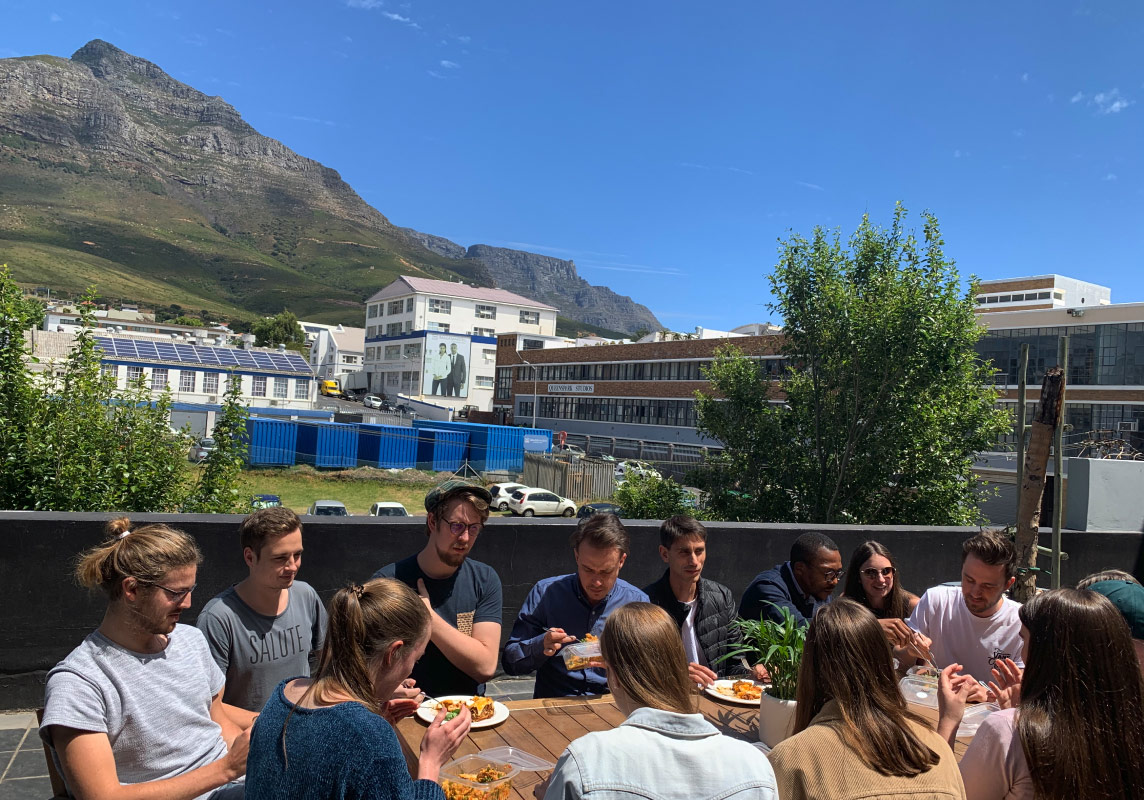 Team sitting on bench enjoying lunch on a beautiful day.