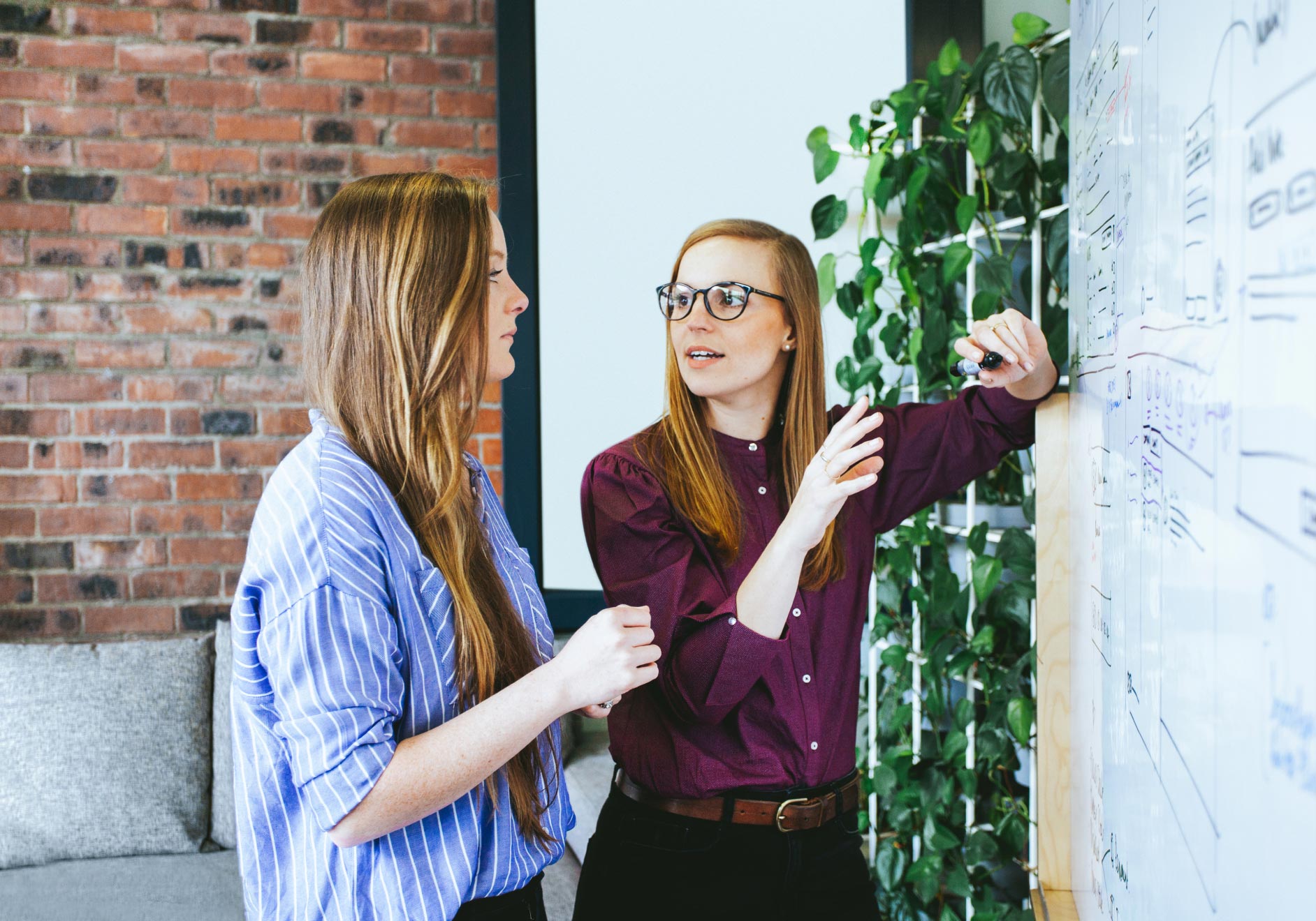 Team members Amy and Mri discussing UX wireframes on a whiteboard.