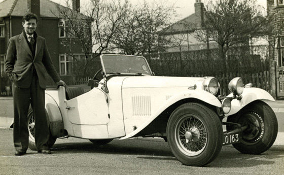 A picture of Bernard Dickinson standing next to a classic car