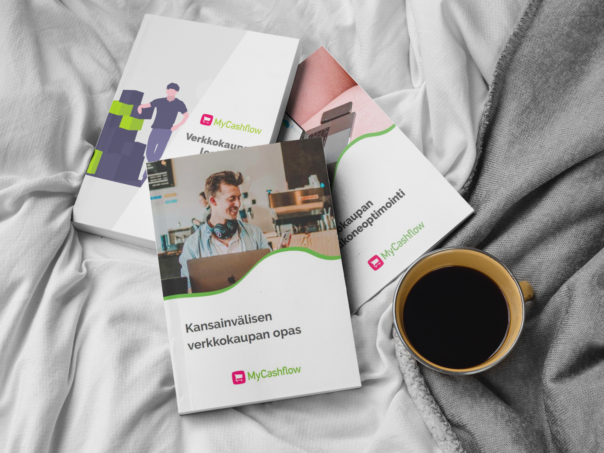 MyCashflow oppaita päällekkäin sängyllä kahvikupin vieressä