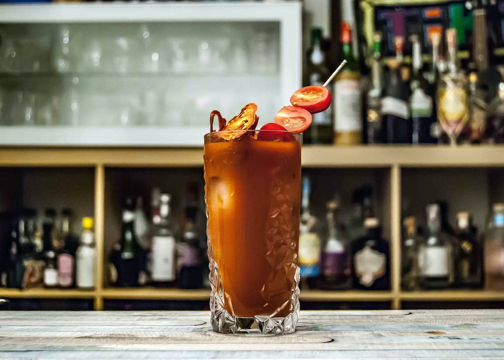 a bloody mary with a tomato skewer garnish