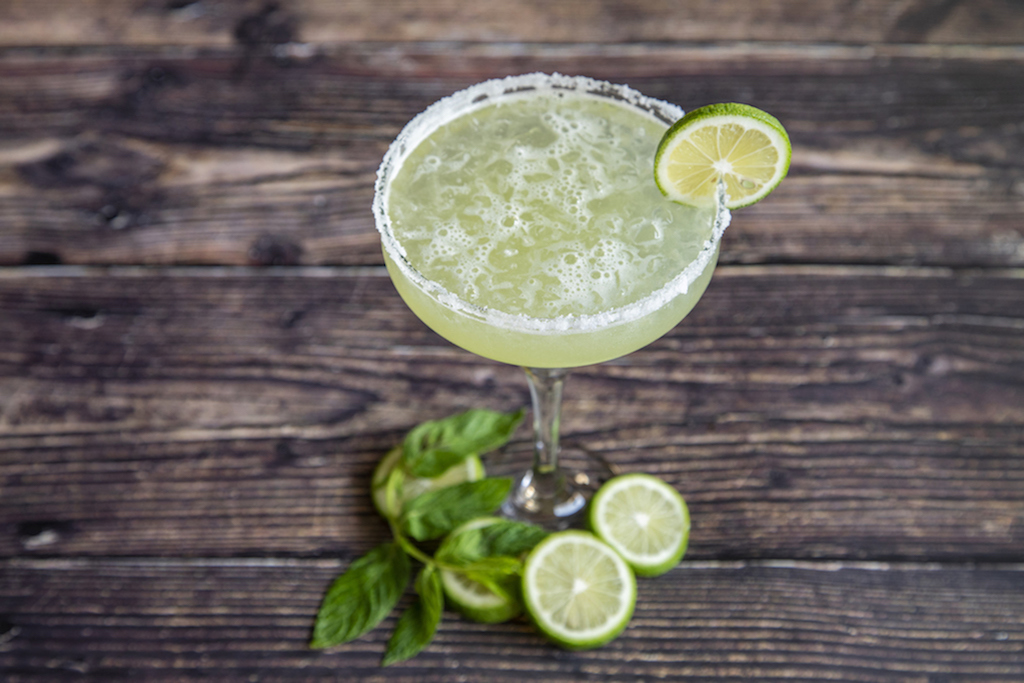 A margarita with a salted rim and lime wheel garnish