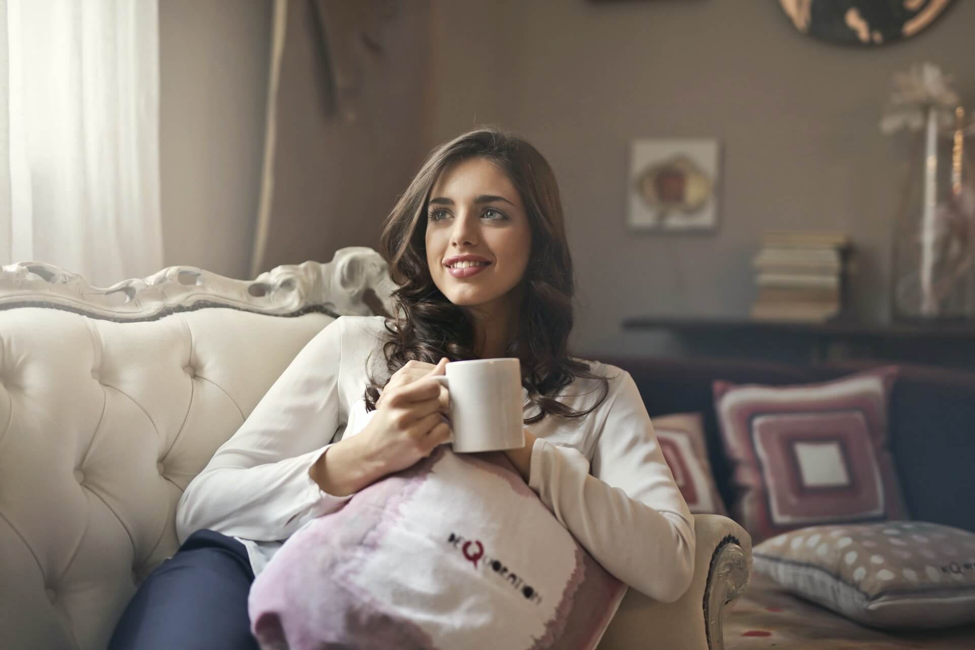 girl with a up of coffee sitting in her living room