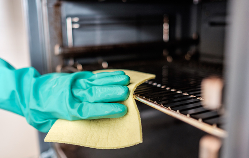 man with a rubber glove wiping down the oven
