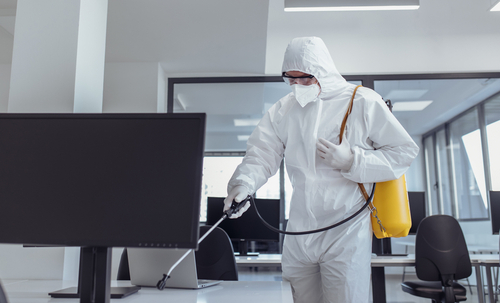 man in white protection suite disinfecting a commercial office space