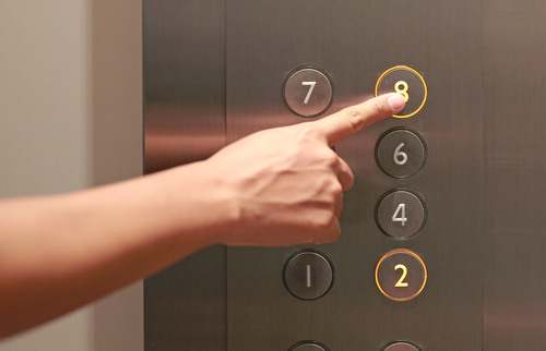 woman pushing lift buttons in an office building