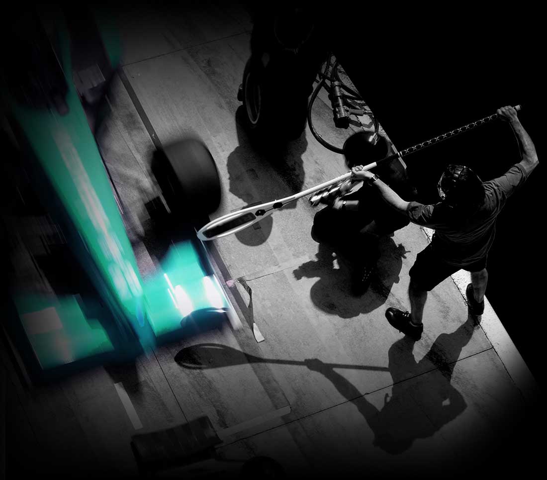 A formula car pulling in for a pit stop with a lolly pop man