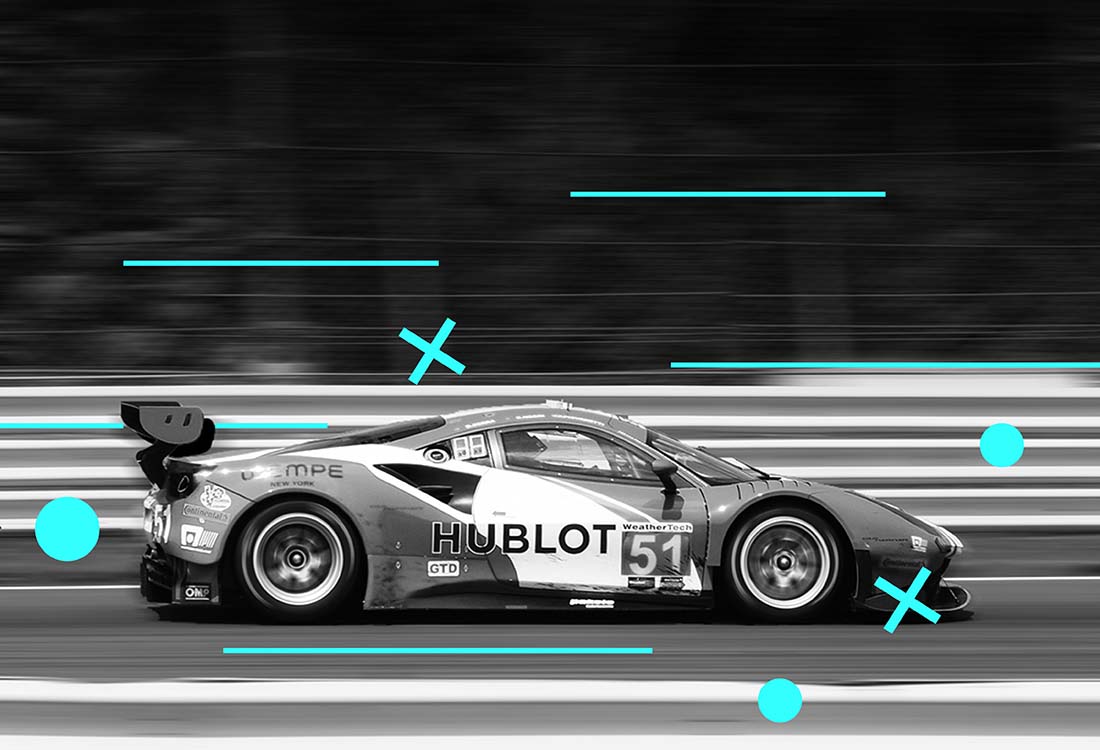 A Ferrar 458 GT3 Car zooming past with ikoniqa's teal graphics flying around the car