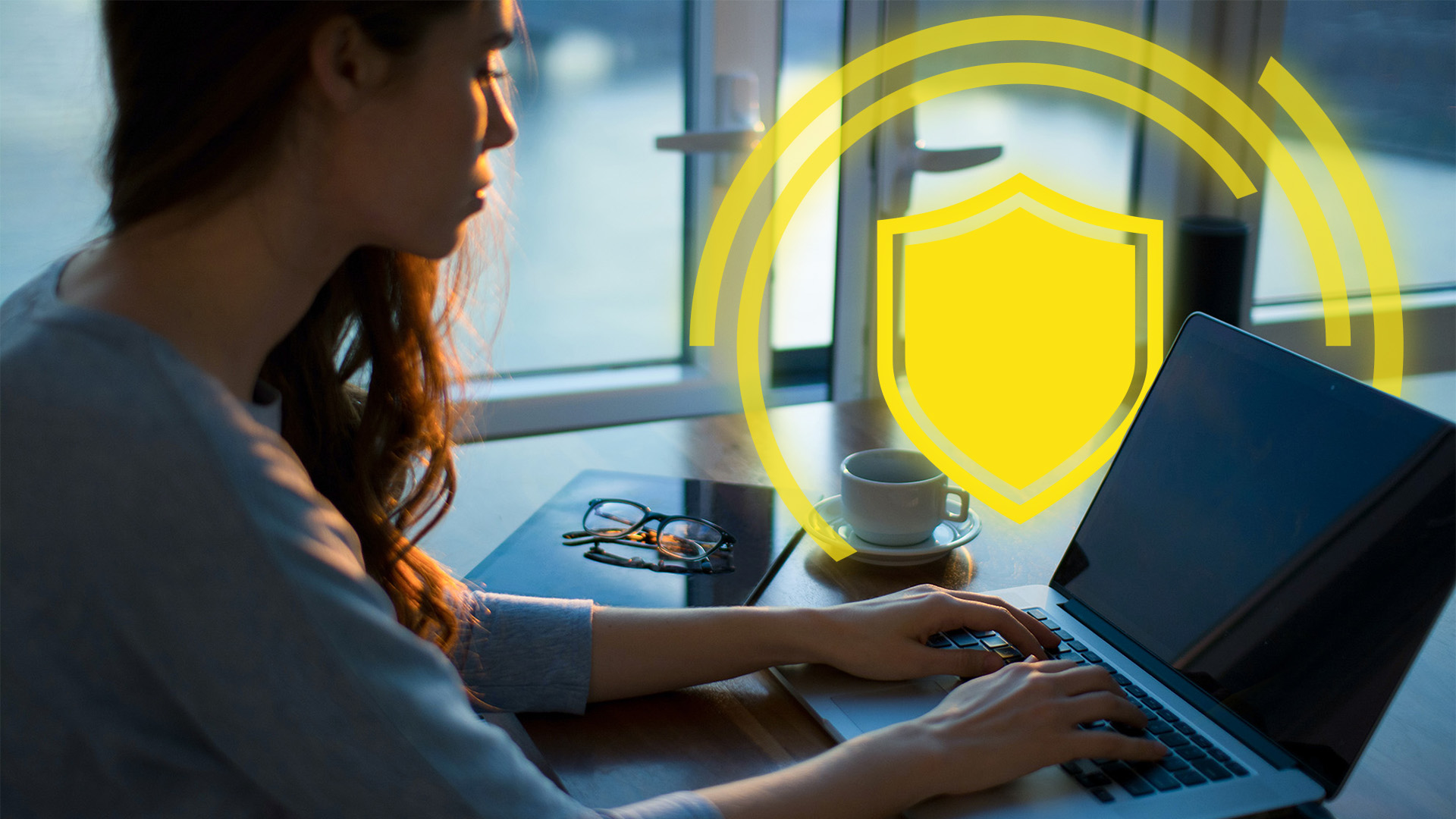 Woman working on a laptop with a glowing yellow badge in the background.