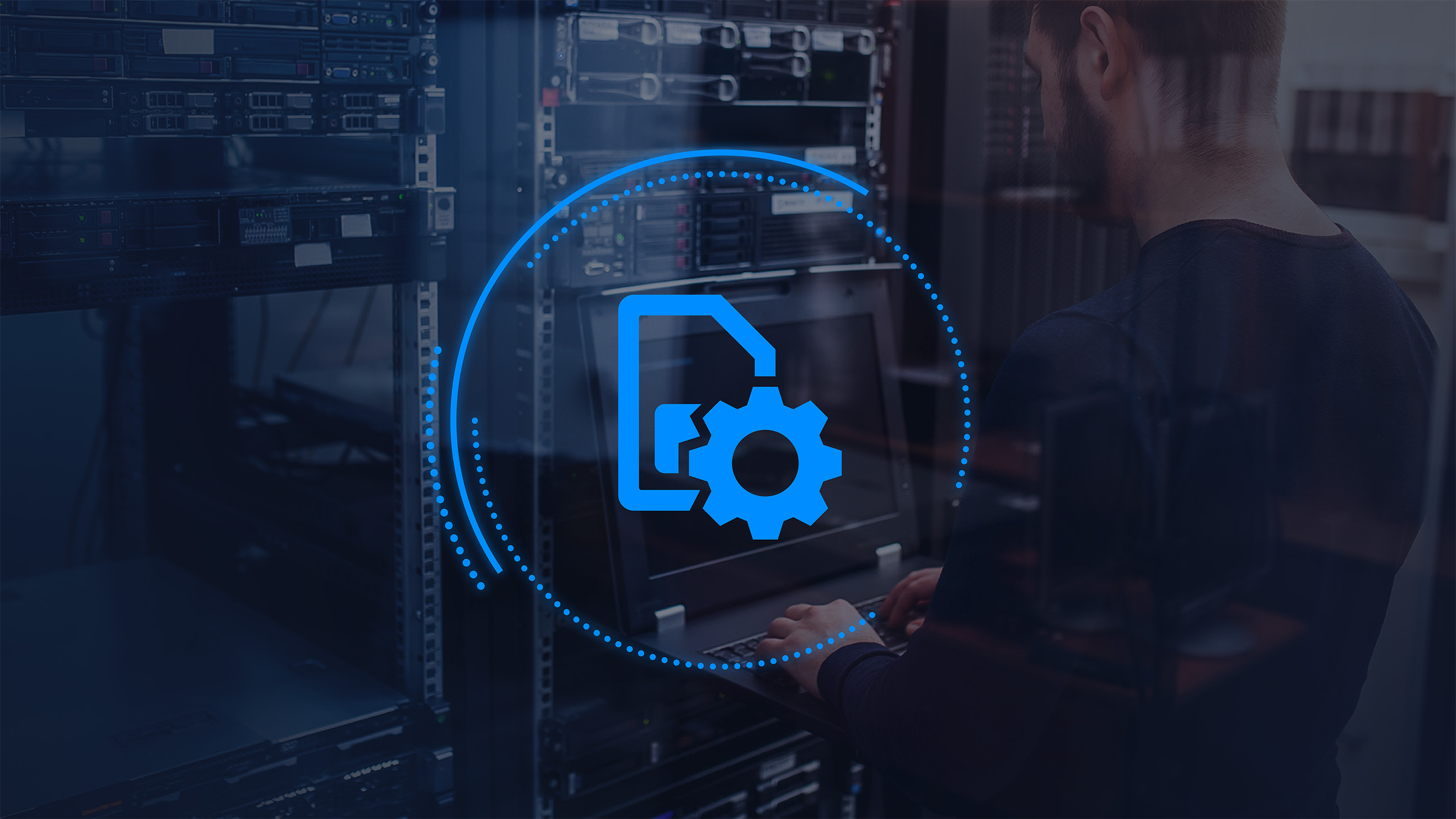 man standing up looking at a computer and computer equipment with a graphic overlay of a gear icon