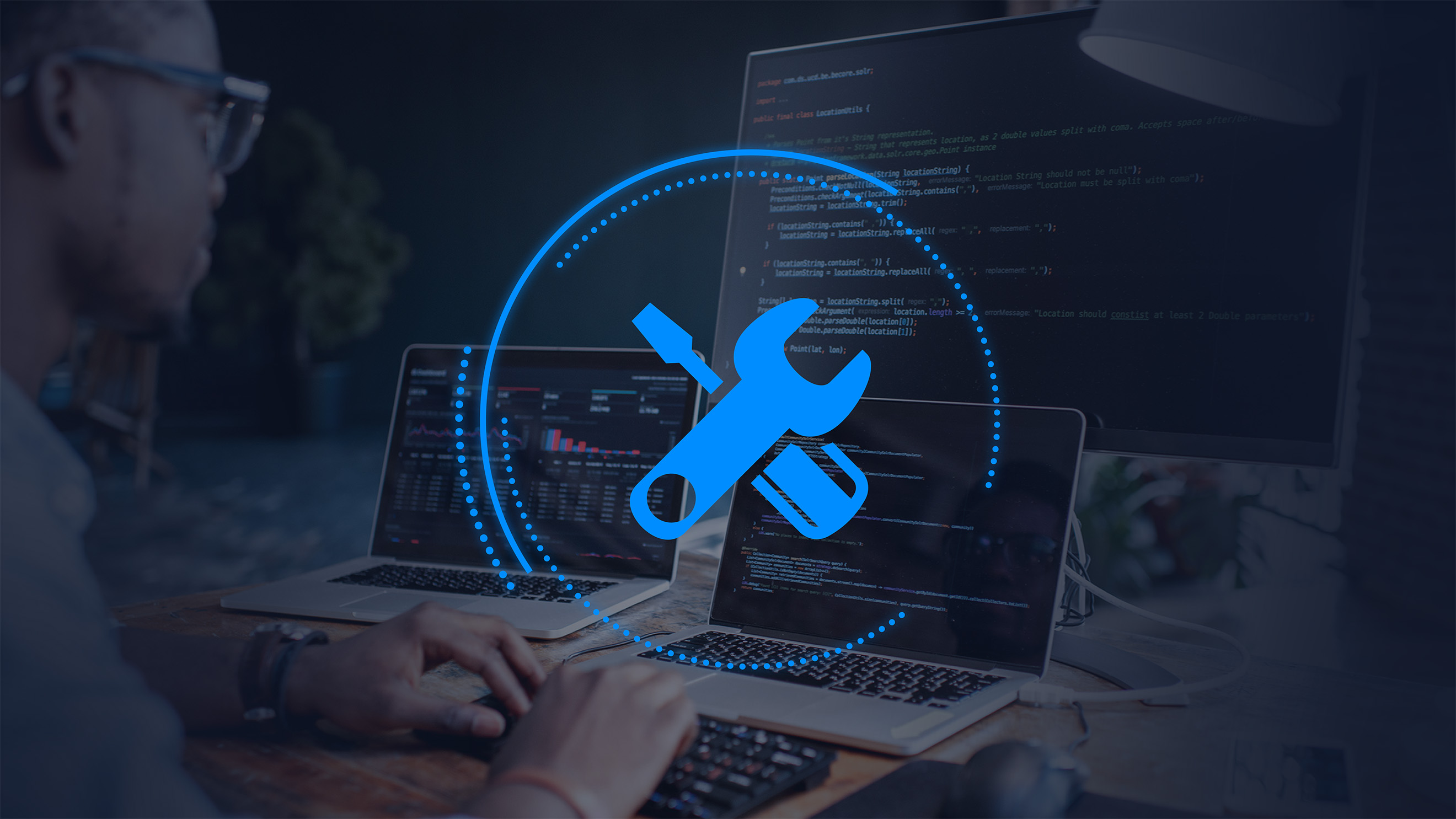 Man looking at 3 computer screens displaying code with a graphic wrench overlay to indicate security remediation