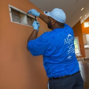 air duct cleaning crew using hose to clean air duct in home