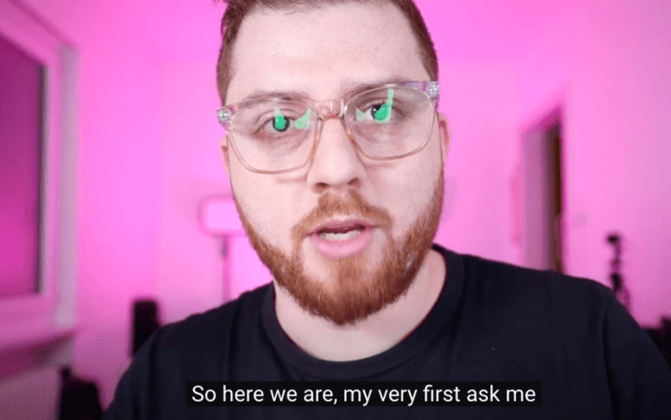 man in camera view with pink background and subtitles on screen