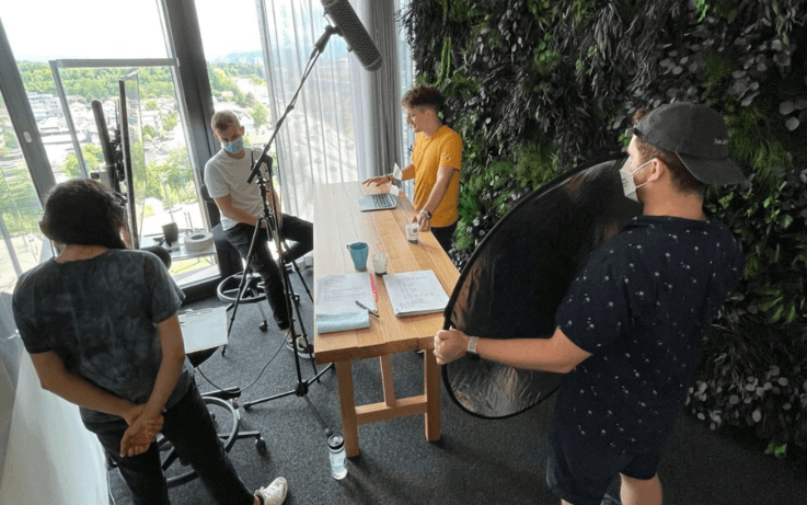 Four men filming a video around large wooden table